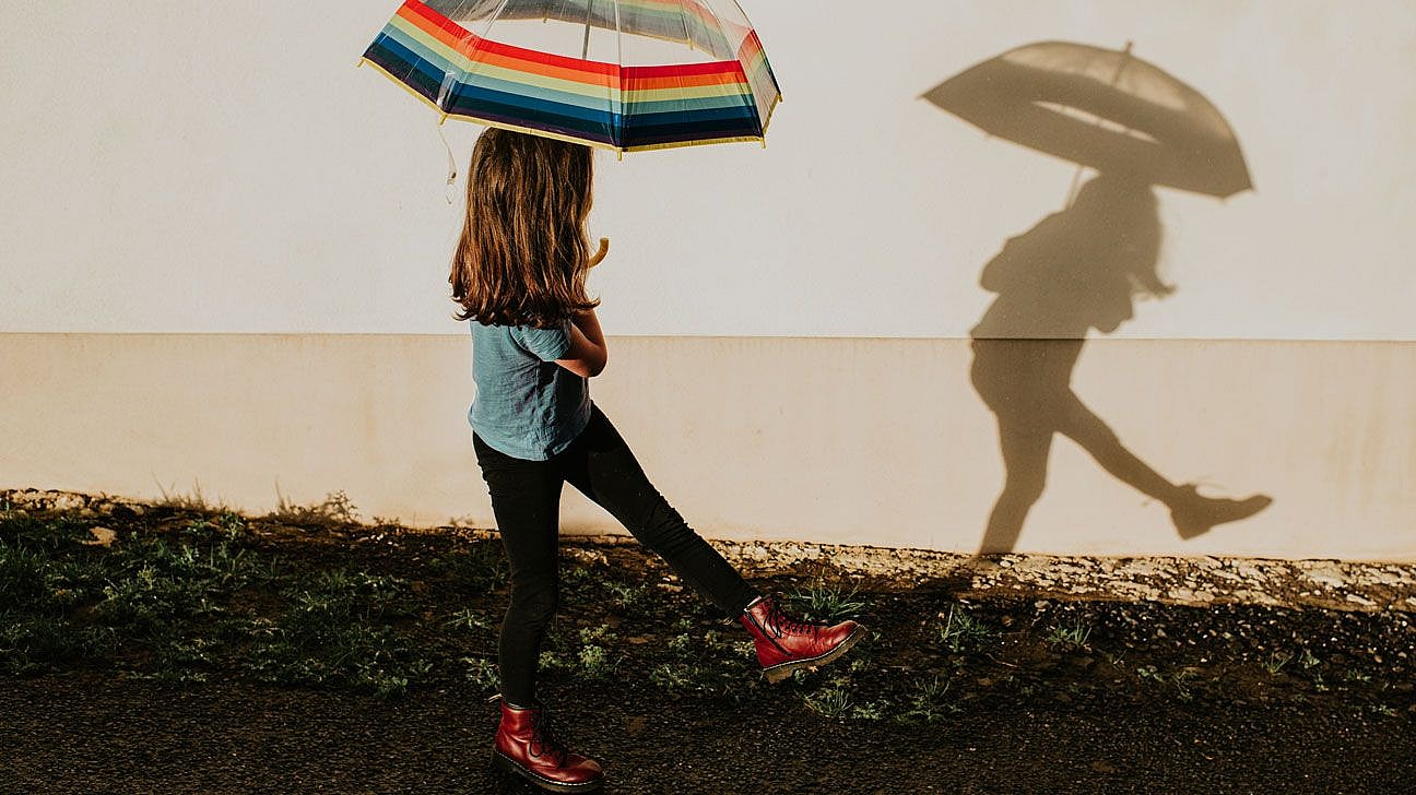 A child with a colorful umbrella playing in the rain.